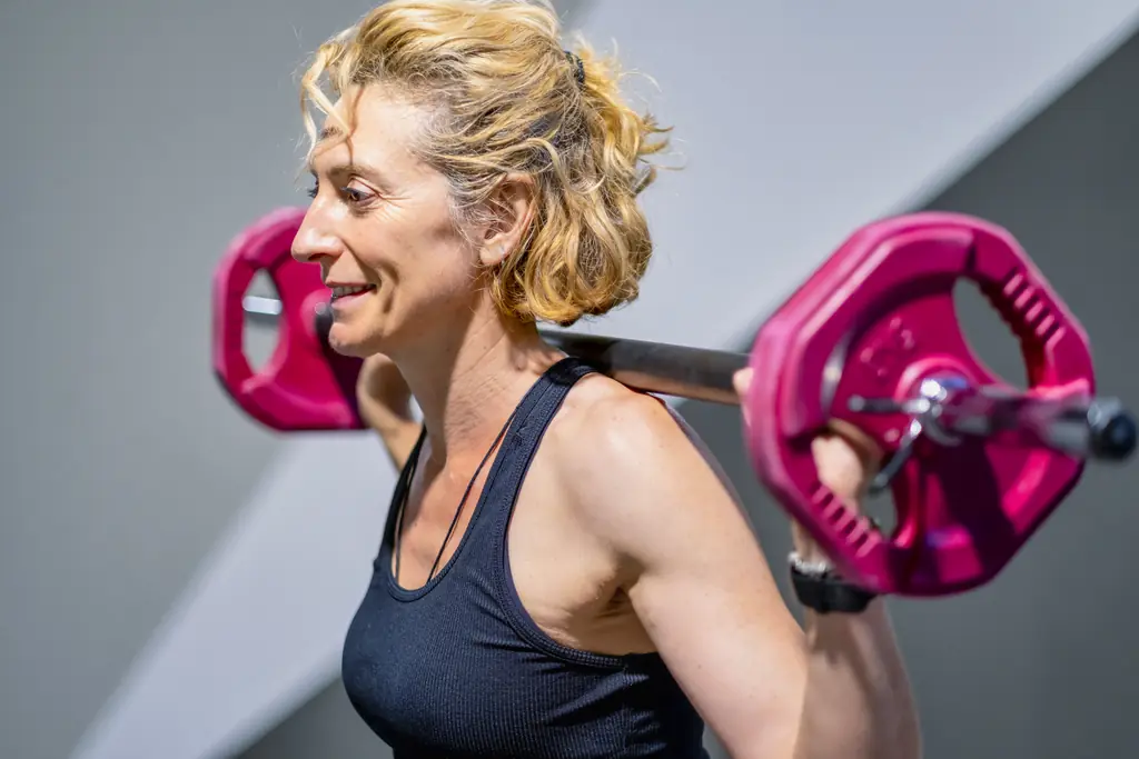 Mujer de 40 años entrenando fuerza con barra y discos