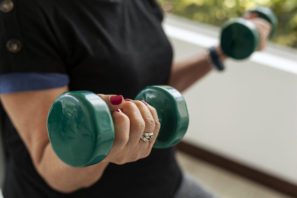 Detalle de las manos de una mujer entrenando fuerza con mancuernas