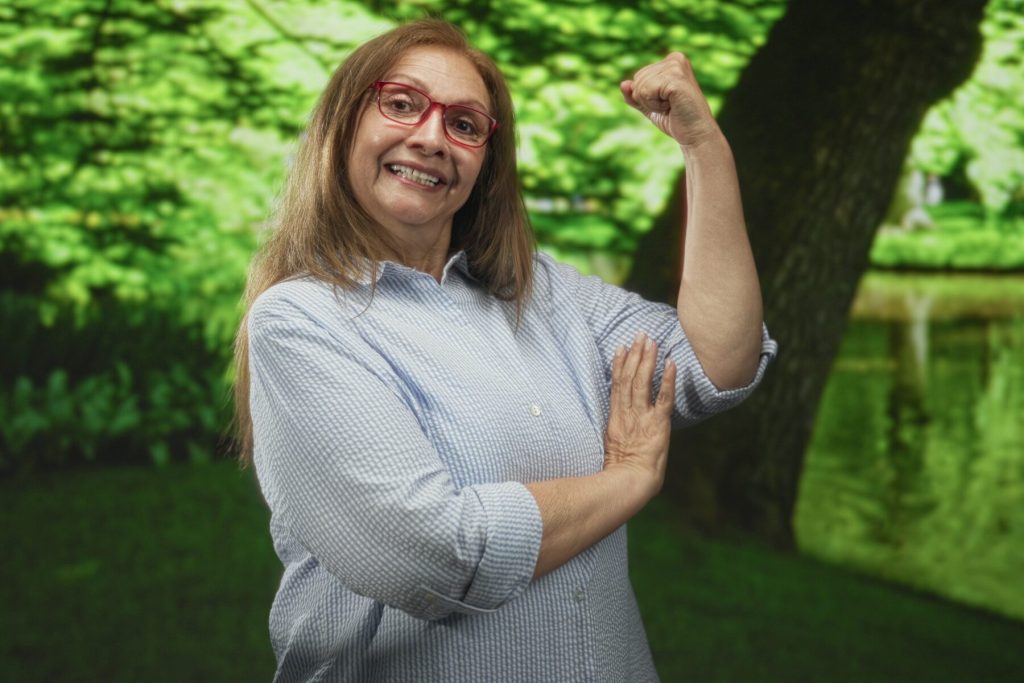 Mujer fuerte de 40 años mostrando su bíceps al aire libre, símbolo de autonomía