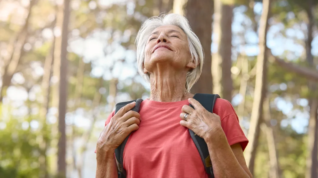 Mujer madura con mochila disfrutando de la naturaleza
