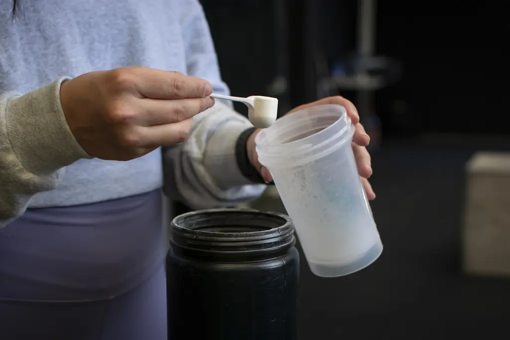 Proteína whey en polvo con cuchara dosificadora y shaker